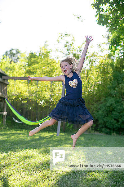 Porträt eines Mädchens,  das im Garten in die Luft springt
