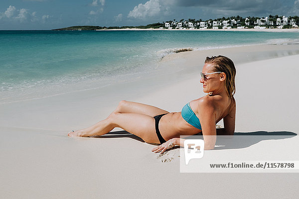 Frau im Bikini am Strand liegend mit Blick auf das blaue Meer  Anguilla  Saint Martin  Karibik