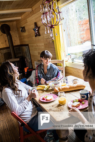 Three friends sitting around table  eating breakfast