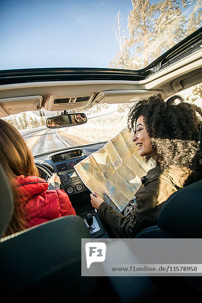 Woman driving car  friend in passenger seat looking at map
