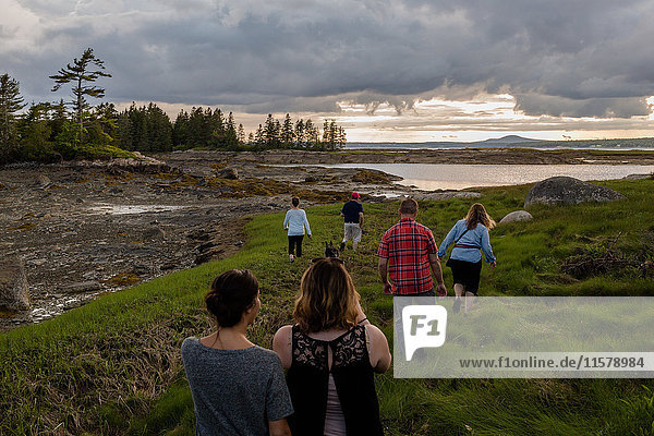 Rear view of adult family walking to coast in Maine  USA