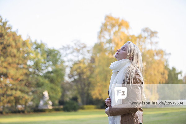 Seitenansicht einer hübschen blonden Frau im Park im Herbst mit geschlossenen Augen