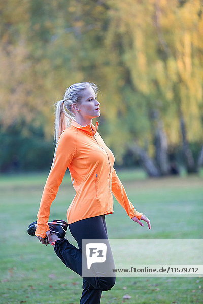 Pretty blonde woman stretching in park
