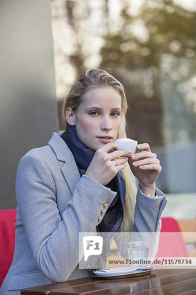 Pretty blonde woman enjoying a cup of coffee in a Cafe and looking at camera