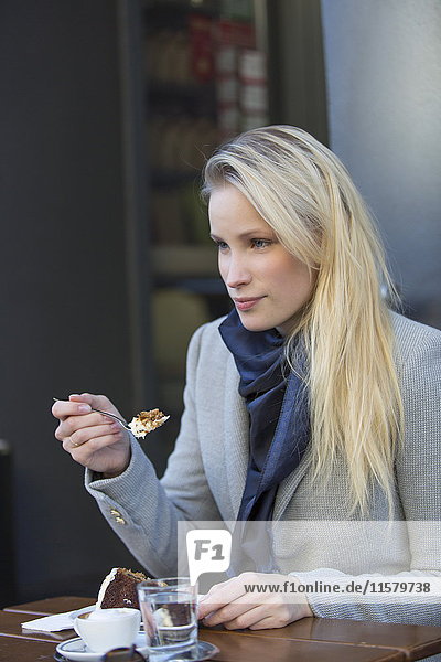 Pretty blonde woman enjoying a cake and coffee in city center