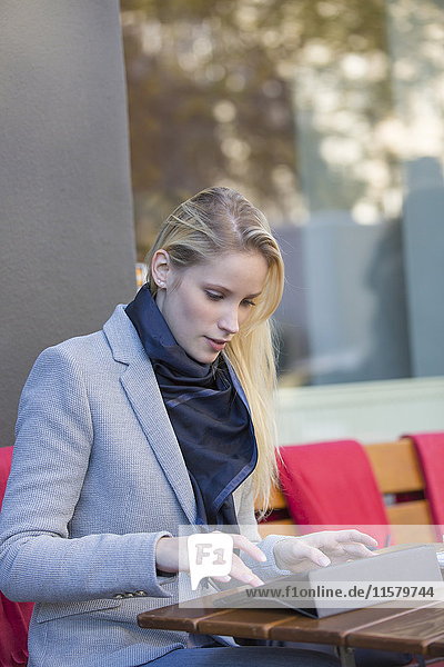 Hübsche blonde Frau mit Tablette in einem Cafe