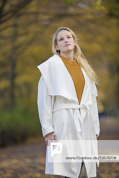 Nachdenklich hübsche blonde Frau mit Mantel im Park im Herbst