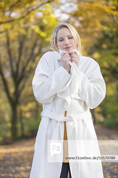 Portrait of a pretty blonde woman with coat in park in autumn