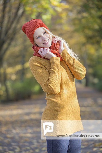 Porträt einer hübschen blonden Frau im Park im Herbst lächelnd vor der Kamera