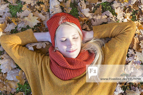 Hübsche blonde Frau im Herbst im Park mit geschlossenen Augen.