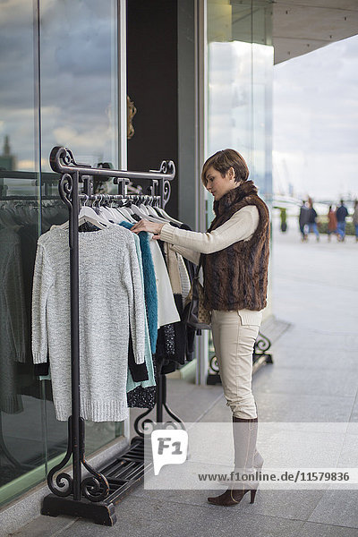 Frau auf der Suche nach Kleidung in einem Geschäft im Freien