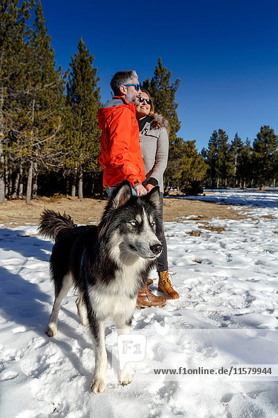 Erwachsenes Ehepaar mit Hund im verschneiten Wald