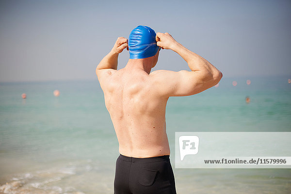 Rear view of mature man adjusting swimming cap on beach  Dubai  United Arab Emirates