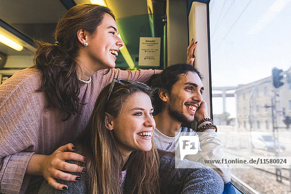 Three friends on train looking out of window at view Lisbon Portugal