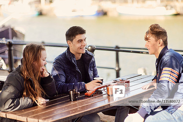 Drei Freunde sitzen im Freien und trinken heiße Getränke  Bristol  UK