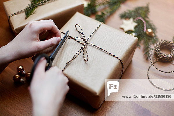 Frau bindet Schleife auf Weihnachtsgeschenk mit Schnur  Nahaufnahme