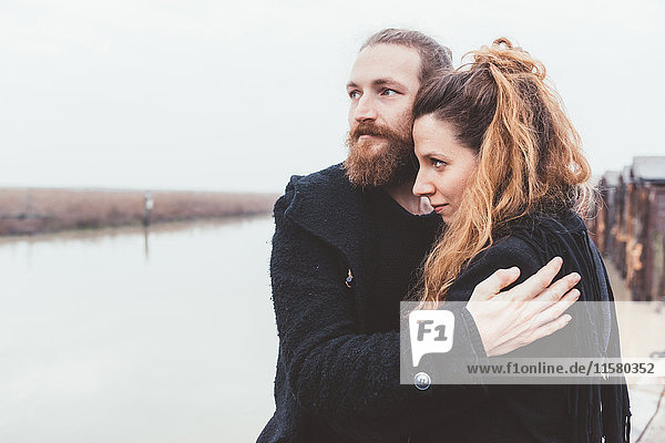 Couple hugging on misty canal waterfront