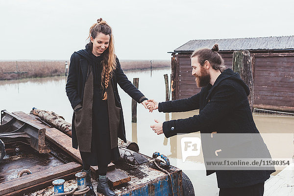 Mann hilft Freundin vom Lastkahn am Kanalufer