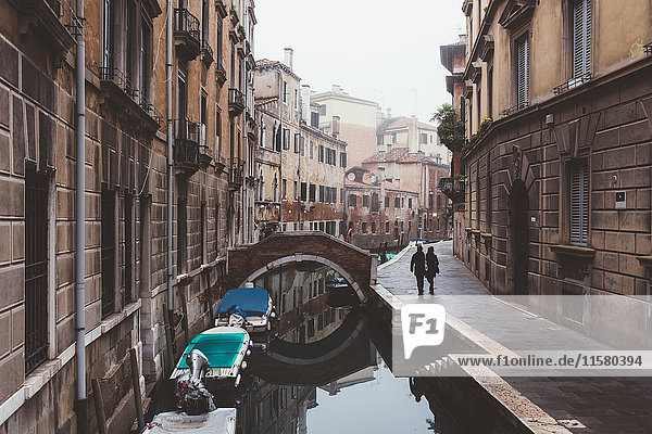 Rückansicht eines Paares  das am Ufer des Kanals spazieren geht  Venedig  Italien