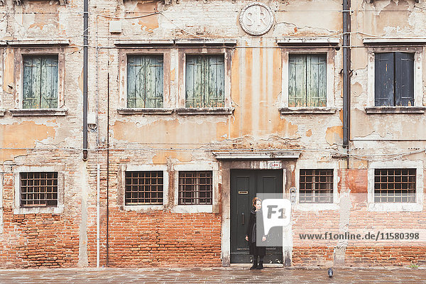 Junge Frau  die vom alten Eingang aus über ihre Schulter schaut  Venedig  Italien