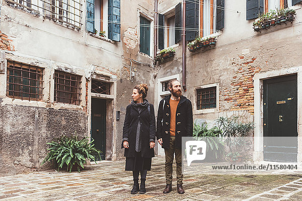 Couple in courtyard looking in opposite directions  Venice  Italy