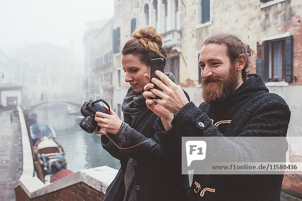 Couple photographing on misty canal waterfront  Venice  Italy