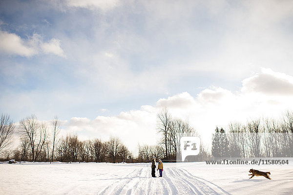 Kinder auf schneebedecktem Weg  die ihren Golden Retriever rufen  Lakefield  Ontario  Kanada