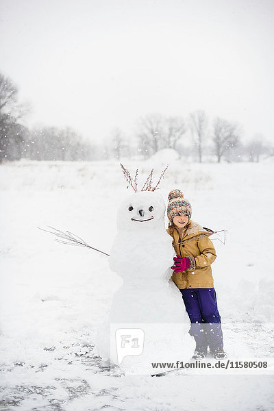 Mädchen schaufelt Schnee vor dem Schneemann  Lakefield  Ontario  Kanada