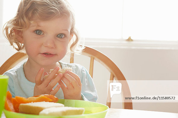 Portrait of cute blue eyed female toddler at kitchen table