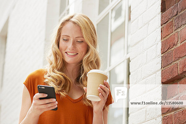 Frau bei Kaffee und SMS in der Straße  London  UK