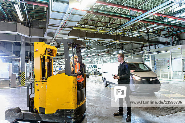 Apprentice engineer with forklift truck in car factory