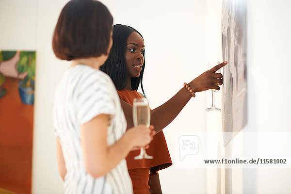 Zwei Frauen zeigen bei der Eröffnung einer Kunstgalerie auf Ölgemälde