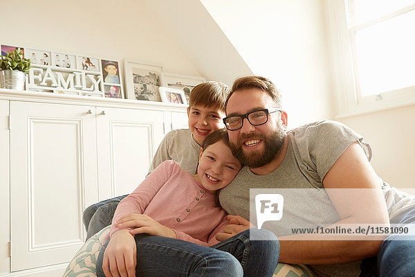 Portrait of mid adult man with son and daughter reclining on beanbag chair