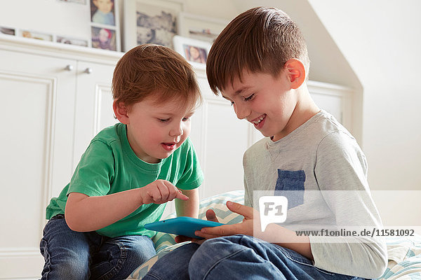 Männliches Kleinkind und Bruder schauen sich digitales Tablet an