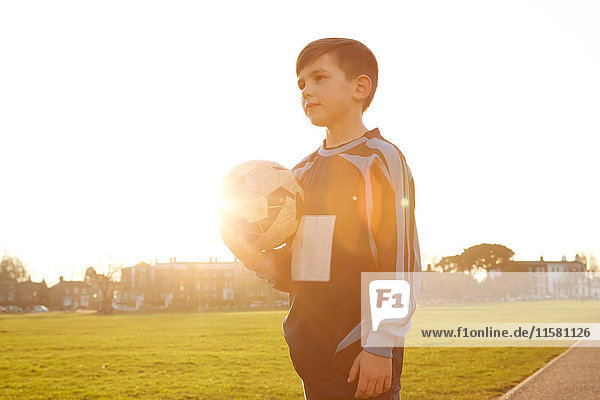 Junge Fußballspieler mit Ball im sonnigen Park