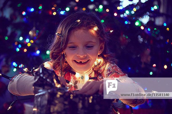 Von Lichtern umgebenes Mädchen packt Weihnachtsgeschenke zu Weihnachten ein