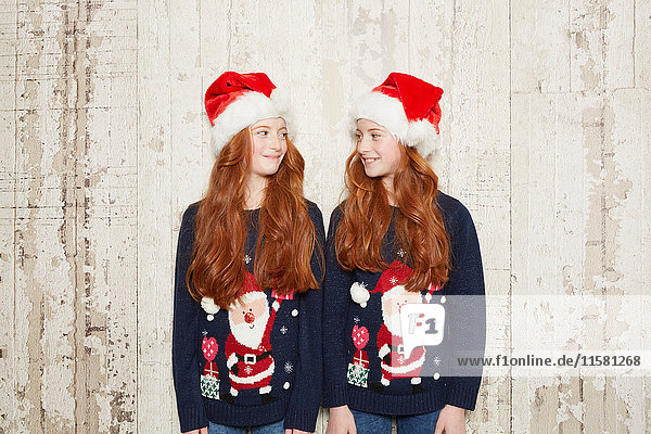 Portrait if twin sisters wearing Christmas jumpers and hats