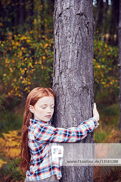 Junges Mädchen  das einen Baum umarmt