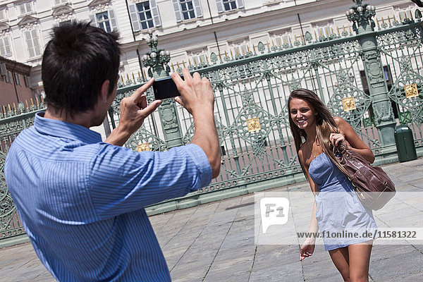 Young man taking photograph of young woman  using smartphone  Turin  Piedmont  Italy