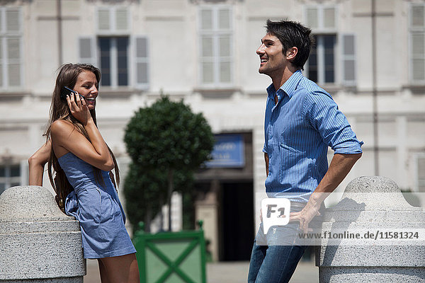 Young couple standing outdoors  young woman using smartphone  Turin  Piedmont  Italy