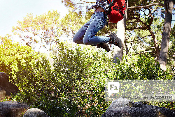 Junge Frau  trägt Rucksack  springt in die Luft  niedriger Abschnitt