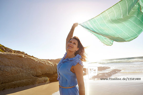 Eine reife Frau steht am Strand und hält einen Schal in der Luft  Kapstadt  Südafrika