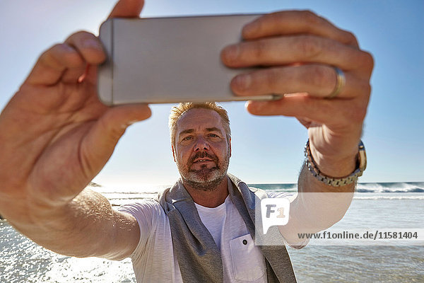 Erwachsener Mann am Strand  Selbsthilfe mit Smartphone  Kapstadt  Südafrika