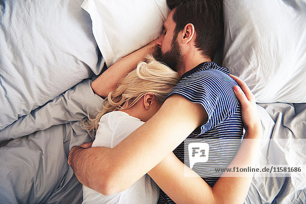 Couple lying in bed together  sleeping  arms around each other