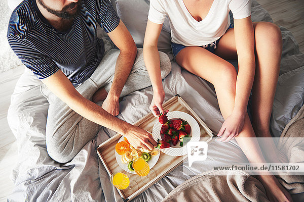 Couple relaxing on bed  eating strawberries  elevated view
