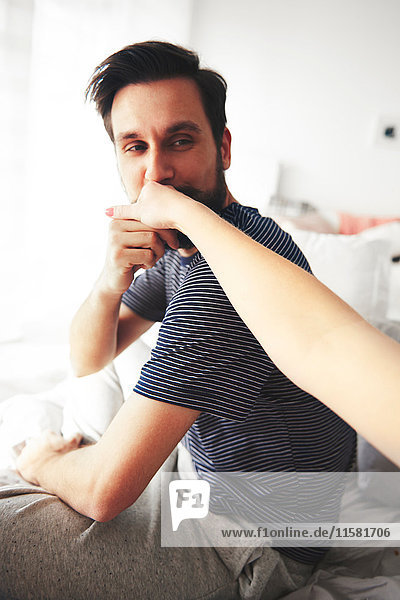 Man sitting on bed  kissing woman's hand