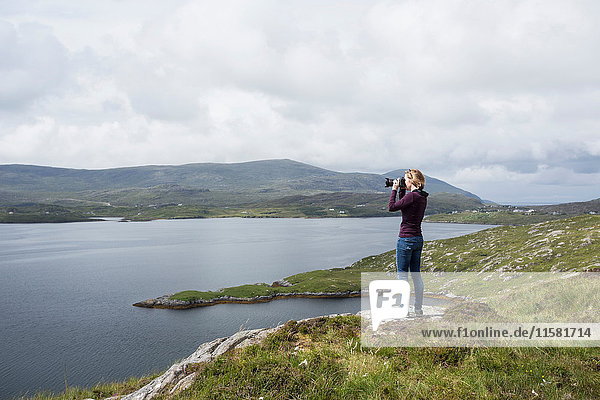 Woman photographing view  standing on north shore of East Loch Tarbet  North Harris  Outer Hebrides  Scotland