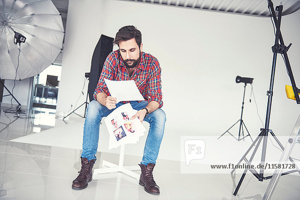 Male photographer looking at photographs in studio