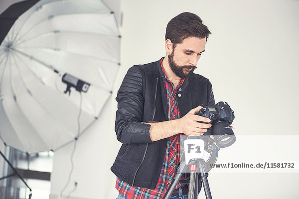 Male photographer reviewing studio photo shoot on digital slr