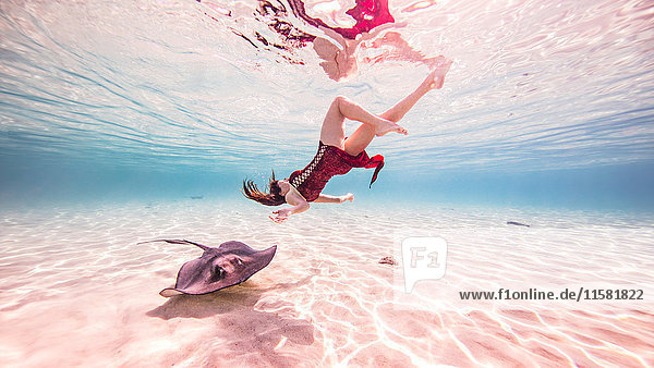 Weibliche Freitaucherin schwimmt in der Nähe von Stachelrochen auf dem Meeresboden